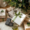 White Marfuga olive oil gift box with green ribbon among wrapped presents under a Christmas tree in a UAE home